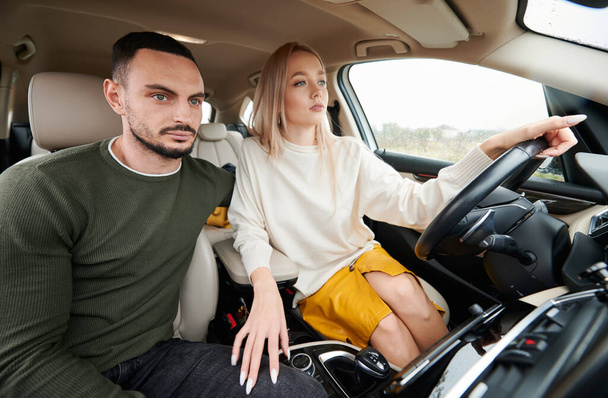 Mann und Frau im Auto unterwegs. Junges Paar sitzt auf Beifahrersitz, während schöne Frau bequemes Auto fährt. - Foto, Bild
