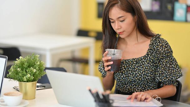 Attrayant pigiste féminine travaillant dans un café, boire du café lors de l'utilisation d'un ordinateur portable au café - Photo, image