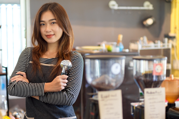 Atractiva belleza asiática barista femenina de pie delante del mostrador y la celebración de portafilter, filtro de café en la cafetería, cafetería - Foto, imagen