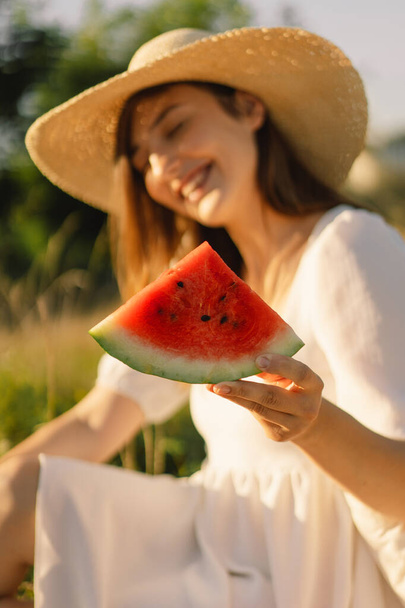 Happy girl in outdoor park with refreshing watermelon fruit. Woman eats a piece of watermelon - Foto, afbeelding
