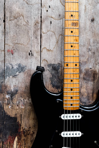 Detalle de Guitarra eléctrica negra sobre fondo de madera. - Foto, imagen