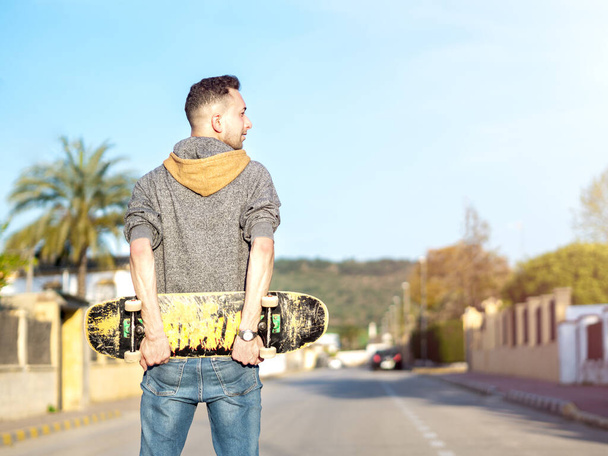 Junger Mann posiert mit Skateboard auf der Straße. Selektiver Fokus - Foto, Bild