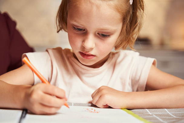Concentrated kid using orange marker for painting picture - Photo, Image