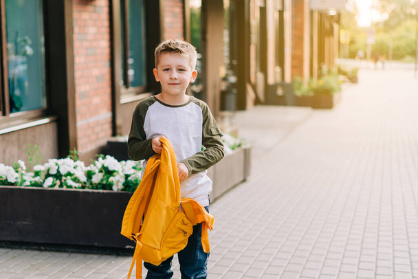 Back to school. Cute child packing backpack, holding notepad and training books going to school. Boy pupil with bag. Elementary school student going to classes. Kid walking outdoor on the city street - Fotoğraf, Görsel