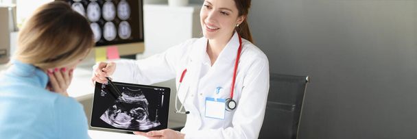 Femme obstétricien gynécologue montrant photo patient de l'examen échographique du fœtus sur tablette numérique - Photo, image