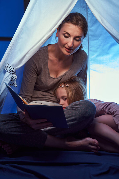 Mädchen schläft im Bettzelt ein, während sie Geschichten hört - Foto, Bild