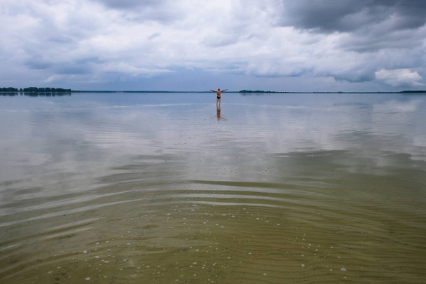 Lago Svitiaz, Volyn, Ucrania. Parque Natural Nacional Shatsky. Un hombre feliz disfruta de la soledad en el fondo del lago en la temporada baja. Copiar espacio. - Foto, imagen