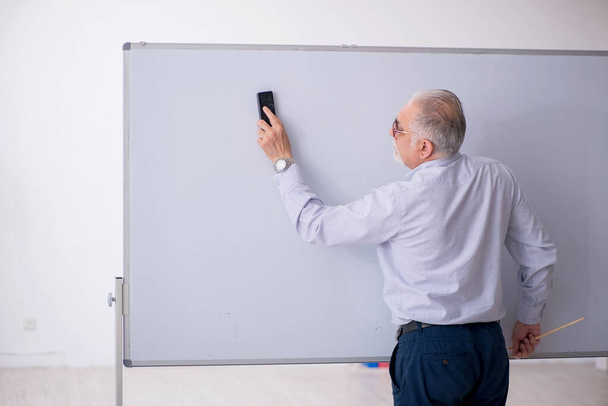 Öreg férfi tanár a tábla előtt. - Fotó, kép