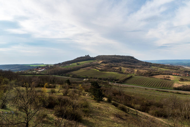 Palava mountains with Stolova hora hill, Sirotci hradk castle ruins and Klentnice village in Czech republic during springtime day with blue sky and clouds - Photo, Image