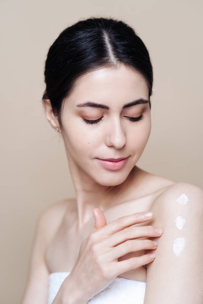 Beautiful Caucasian woman applying cream on face - Foto, imagen