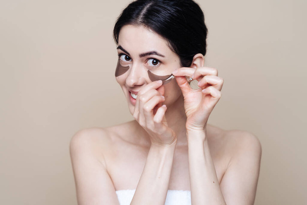 Молодая красивая женщина с чистой свежей кожей лица, использует повязки на глазах - Фото, изображение