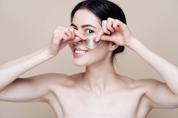 Молодая красивая женщина с чистой свежей кожей лица, использует повязки на глазах - Фото, изображение