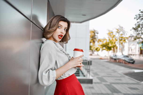 vonzó szőke nő piros szoknya csésze ital szabadban életmód - Fotó, kép