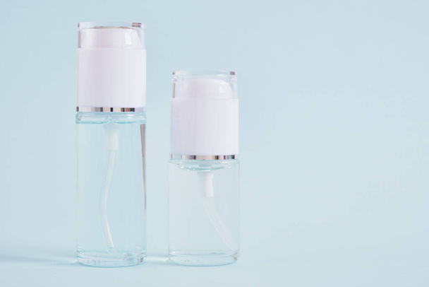 two mock up blank glass bottles with a white cap on a light blue background, cosmetic bottles, bottle with gel and a transparent liquid for skin care or perfume - Fotoğraf, Görsel
