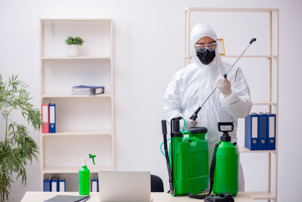 Young male contractor disinfecting office during pandemic - Photo, Image