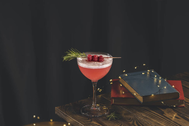 Elegant glass of raspberry cocktail with egg, decoration fresh berries on rosemary branch. Club cocktail. Sour drink with gin, raspberries, and egg white foam. Close up, shallow depth of the field. - Photo, Image