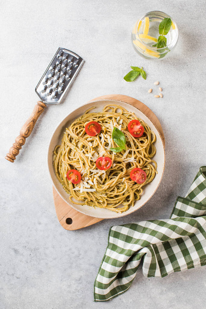 Spaghetti pasta with pesto sauce and cherry tomatoes, glass of water. Top view - 写真・画像
