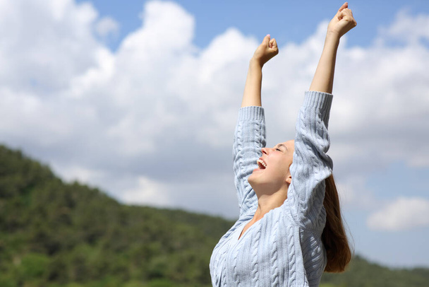 Side view portrait of an excited woman celebrating raising arms outdoors - Φωτογραφία, εικόνα