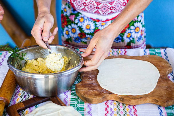 image avec les mains d'une dame cuisinant des tartes roumaines traditionnelles avec du fromage dans des vêtements traditionnels. - Photo, image