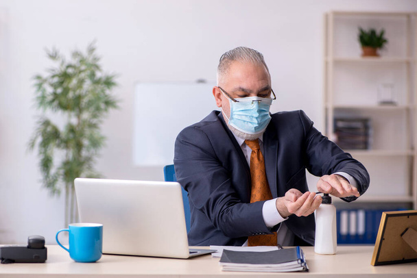 Ancien employé masculin travaillant dans le bureau pendant la pandémie - Photo, image