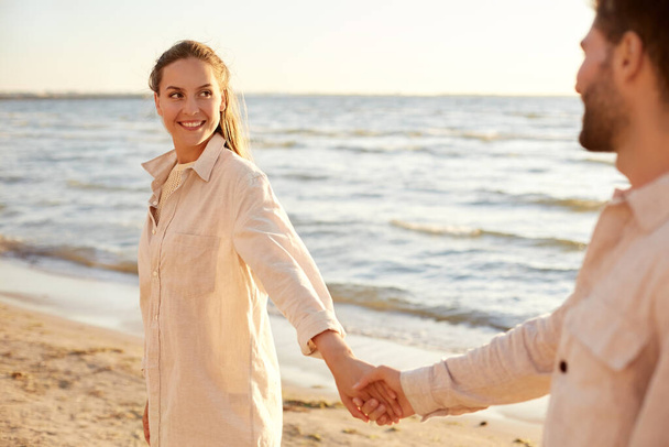happy couple holding hands on summer beach - Valokuva, kuva