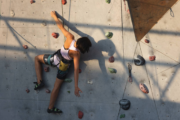 Dziewczyna wspina się na ścianę wspinaczkową. wspinaczka skalna jako rodzaj aktywnego wypoczynku w mieście. uprawianie sportu w przyrodzie - Zdjęcie, obraz