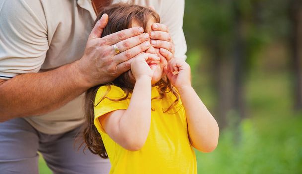 Onnellinen isä yllätti tyttärensä keltaisessa t-paidassa ja sulki hänen silmänsä. Isi päivä käsite. - Valokuva, kuva