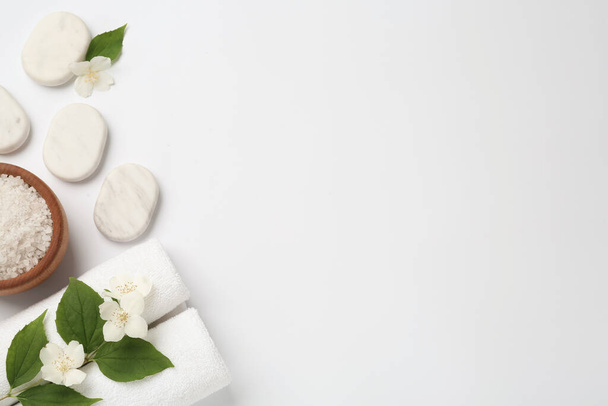 Spa stones, beautiful jasmine flowers, sea salt and towels on white background, flat lay. Space for text - Foto, Imagem