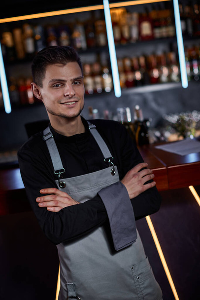 Handsome barman in apron standing at the bar counter - Foto, imagen
