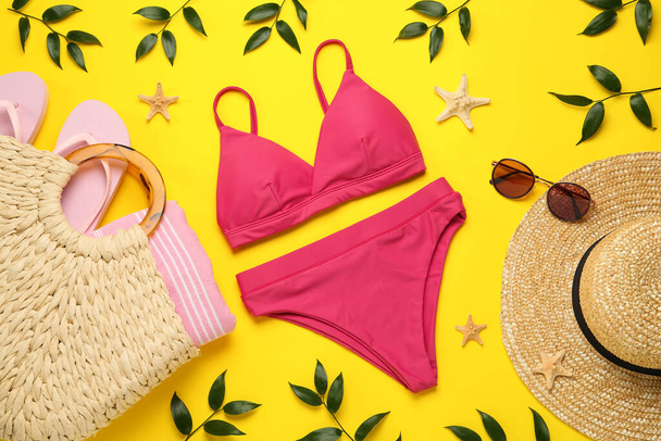 Stylish bikini and beach accessories on yellow background, flat lay - Фото, изображение