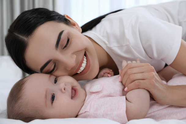 Young mother with her little baby on bed at home - Foto, imagen