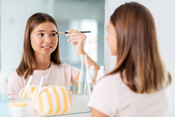 teenage girl applying eye shadow at bathroom - Foto, immagini