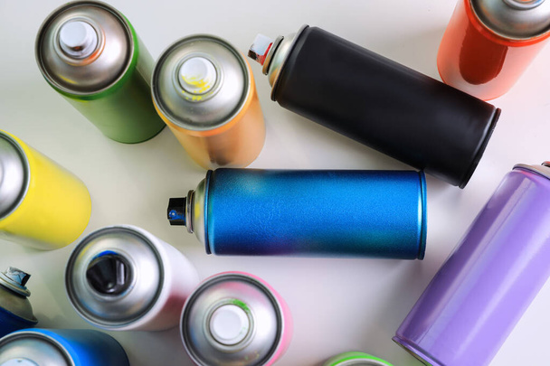 Cans of different graffiti spray paints on white table, flat lay - 写真・画像