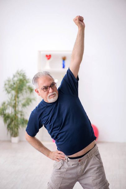 Starý muž dělá sportovní cvičení uvnitř - Fotografie, Obrázek
