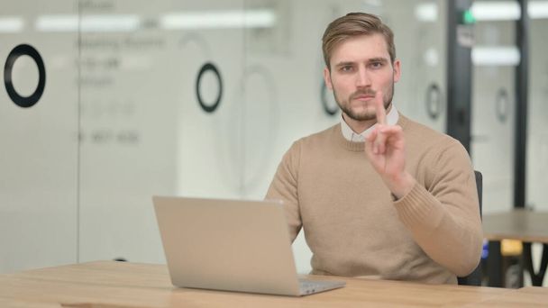 Fiatal férfi mutatja nincs jel, miközben dolgozik a Laptop  - Fotó, kép