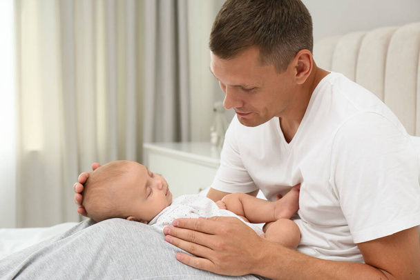 Happy father holding his cute sleeping baby on bed at home - Φωτογραφία, εικόνα