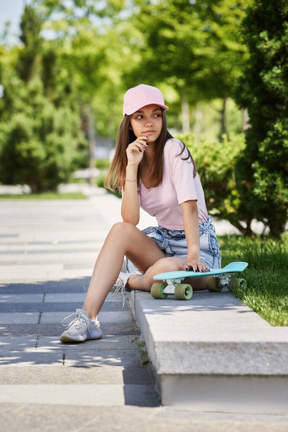 beautiful skateboarder girl with skateboard sitting outdoors - Fotoğraf, Görsel