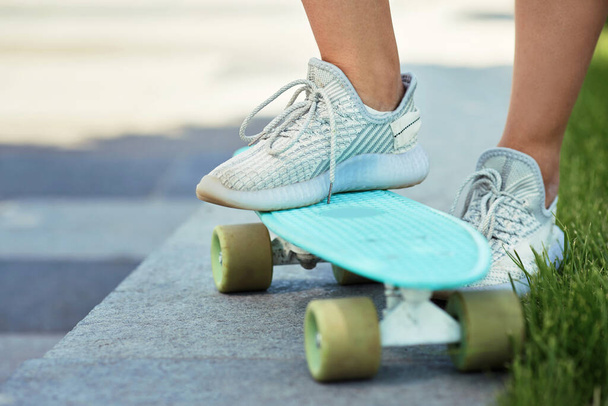 женские ноги стоят на синем скейтборде в парке - Фото, изображение
