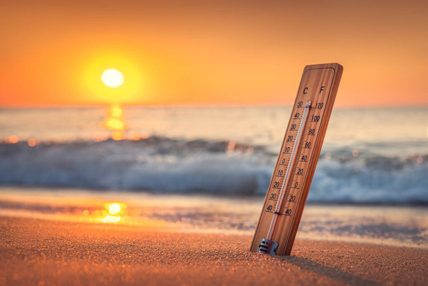Termómetro y salida del sol sobre la playa. El calor. Día caliente de verano.  - Foto, imagen