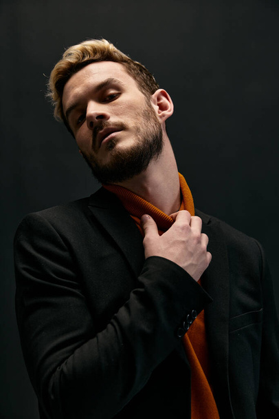 blond man raakt zijn nek en oranje trui trend van het seizoen mode stijl - Foto, afbeelding