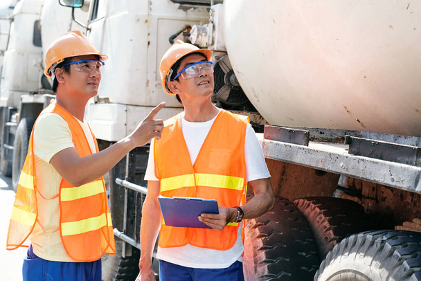 Bauunternehmer diskutieren, wo Zementmischer geparkt werden sollen - Foto, Bild