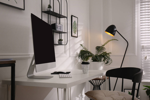 Comfortable workplace with modern computer and houseplants in room. Interior design - Zdjęcie, obraz