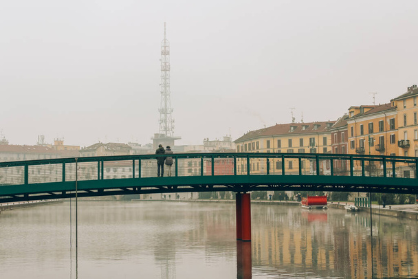 アレクサンダー・ランガー橋、霧深い冬の朝のダルセナ海岸、ミラノ市、ナヴィリ地区に立っている認識できないカップル。観光地のコンセプト - 写真・画像