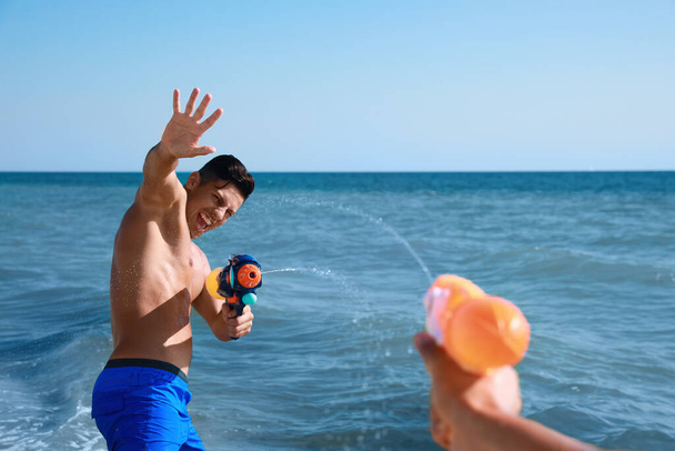 Friends with water guns having fun in sea - Photo, image