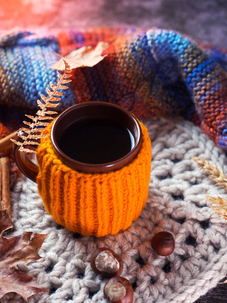 ニットオレンジセーター付きのカップに熱い秋のコーヒーや紅茶と秋の組成物。ニットスタンドと暖かいカラフルなスカーフ - 写真・画像
