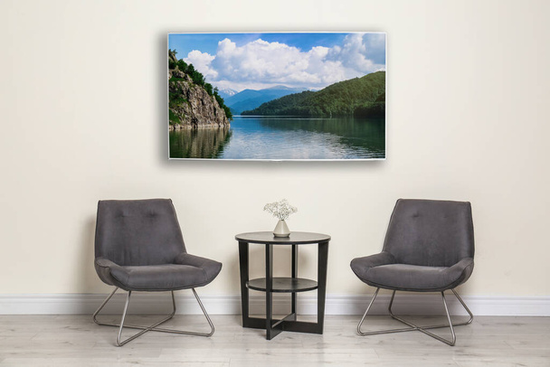 TV moderne grand écran sur mur blanc dans la chambre avec des meubles élégants  - Photo, image