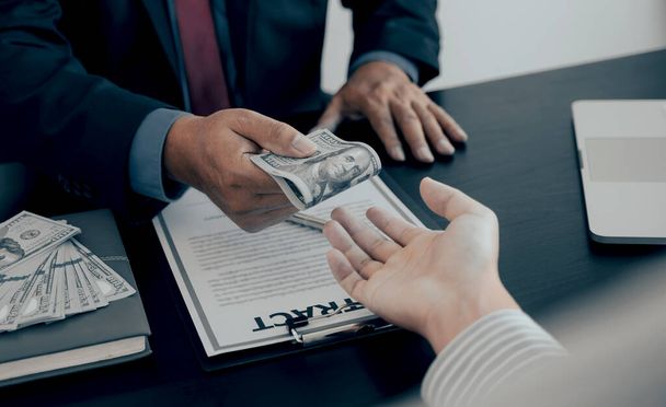 Zakenman hand houden dollar bankbiljet geld om financiële ambtenaren om te kopen of Boss is uitbetaling personeel salaris en anti-omkoping. - Foto, afbeelding