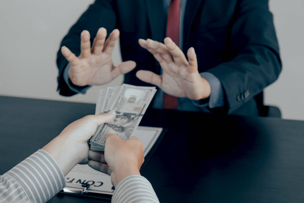Бізнесмен дає хабар урядовим чиновникам, які піднімають руку, відмовляючись від грошей концепція корупції та хабарництва
. - Фото, зображення