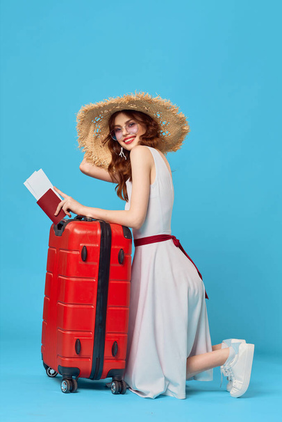 красивая женщина в шляпе с красным чемоданом на синем фоне. Высокое качество фото - Фото, изображение