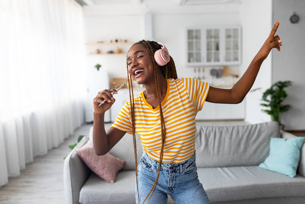 Huoleton afro amerikkalainen pitkätukkainen nainen laulaa ja tanssii älypuhelimella - Valokuva, kuva
